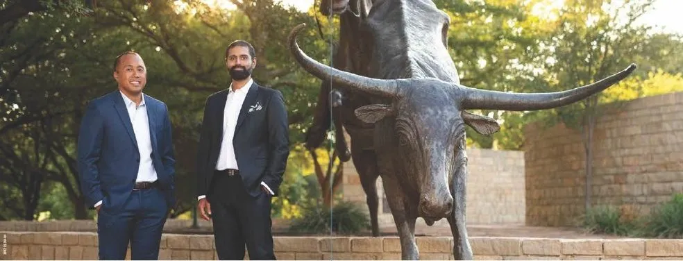 Two men in suits by a longhorn statue.