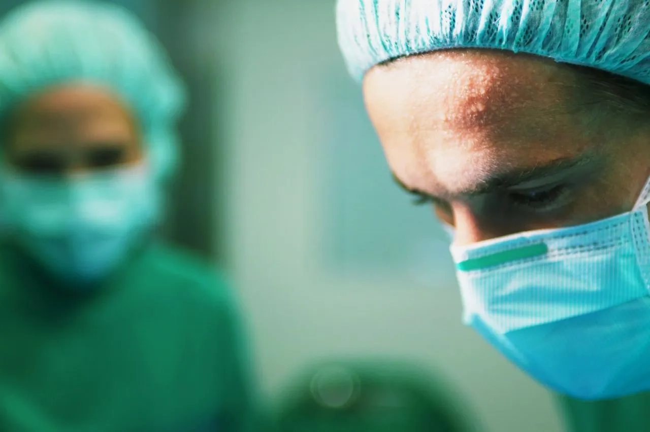 Surgeon in scrubs during operation.